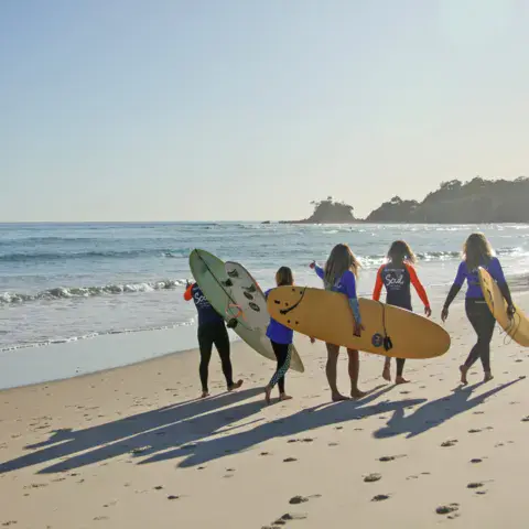 Élèves avec leurs planches de surf sur la plage