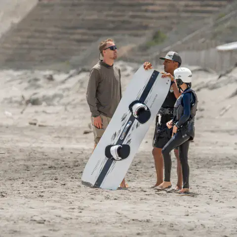 Moniteur et élève avec une planche de kitesurf sur la plage