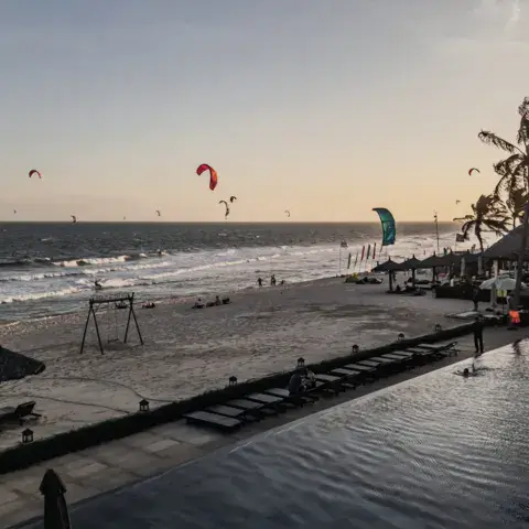Plage et piscine de l'hébergement, avec des kites au large