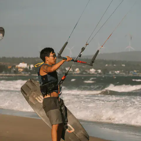 Kitesurfeur qui rentre sur la plage avec sa planche