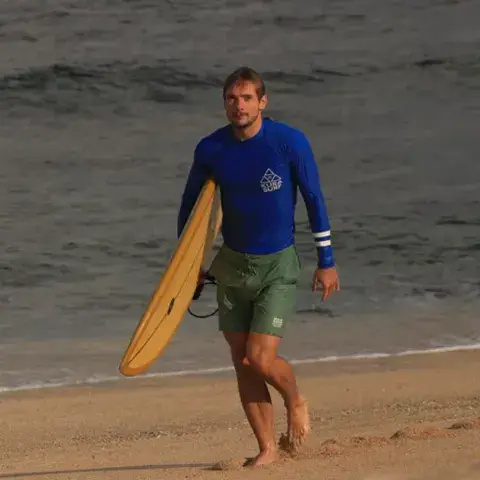 Un surfeur sort de l'eau avec sa planche