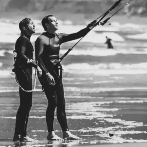 Moniteur et élève sur la plage, kitesurfeur au loin