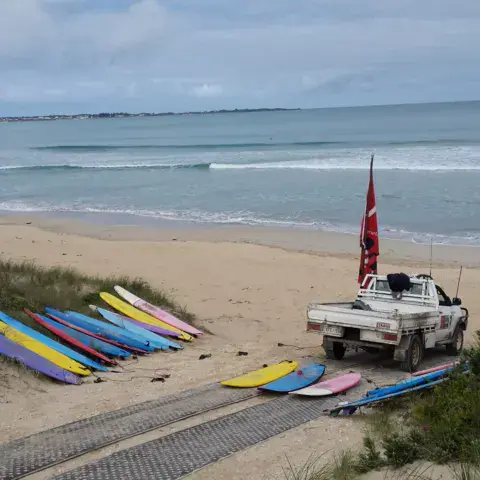 Planches alignées sur le sable à côté du véhicule de l'école