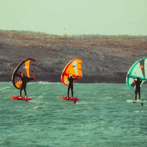 Trois pratiquants de wing foil sur le lac