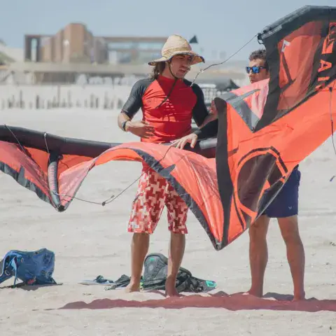 Préparation d'une aile de kitesurf sur la plage