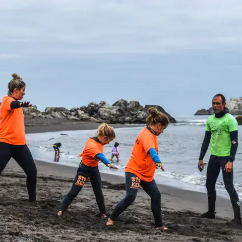 Échauffement de moniteurs et d'élèves sur la plage de sable noir