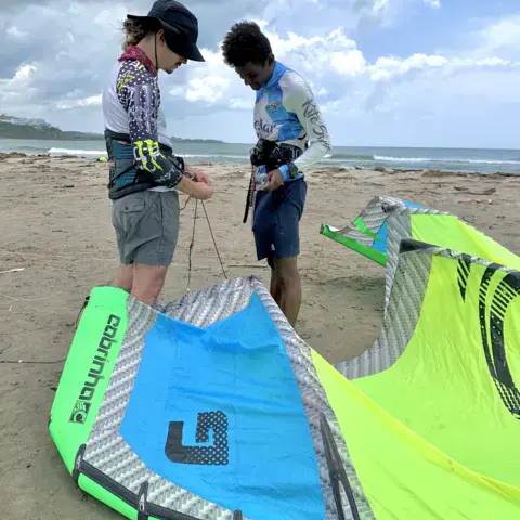 Un moniteur et un élève préparent l'aile sur la plage
