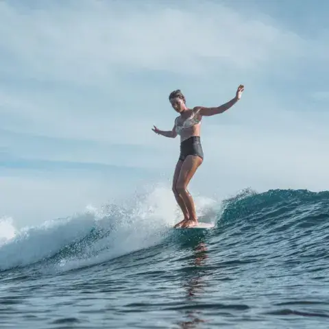 Surfeuse en longboard sur une vague