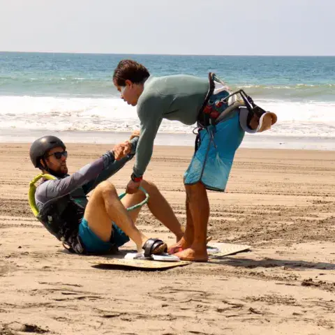 Moniteur aidant un élève avec sa planche sur la plage