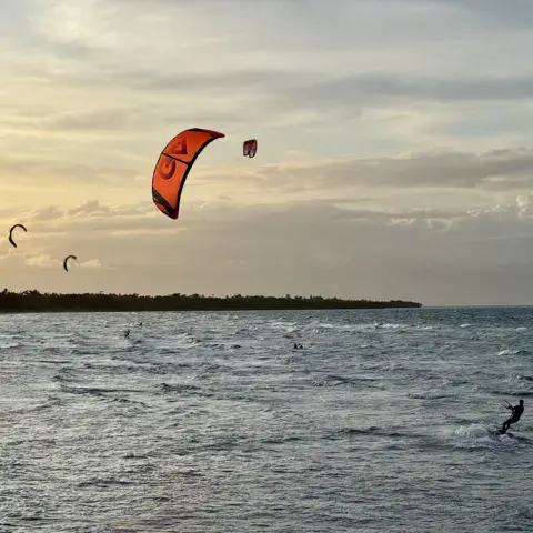 Plage de sable et ailes de kitesurf au soleil couchant