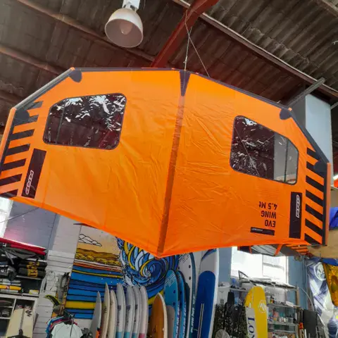 Aile de wing suspendue dans la boutique, planches de surf au fond