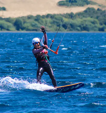 Kitesurfeur casqué tenant sa barre sur un lac