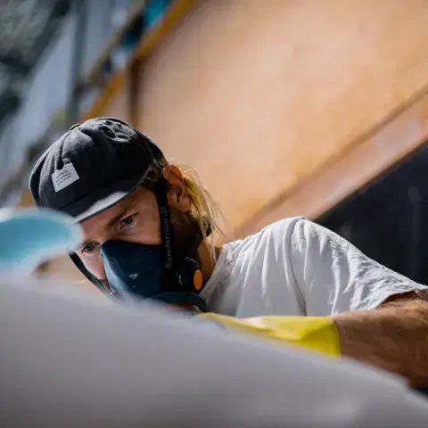 Artisan masqué travaillant sur une planche de surf