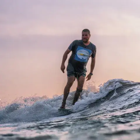 Surfeur sortant de l'eau, planche sous le bras, au crépuscule