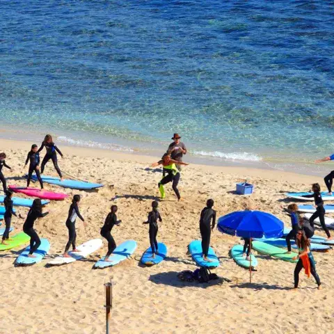 Groupe d'élèves avec leurs planches sur la plage avant la leçon