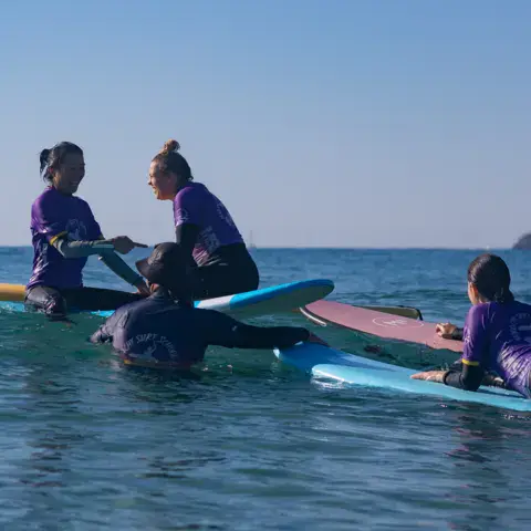 Groupe de surfeurs assis sur leurs planches au large