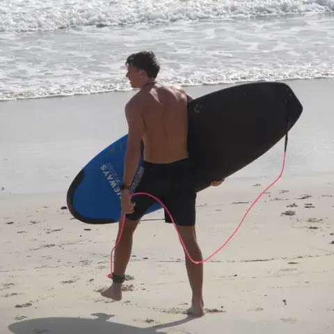 Surfeur de dos portant sa planche sur la plage
