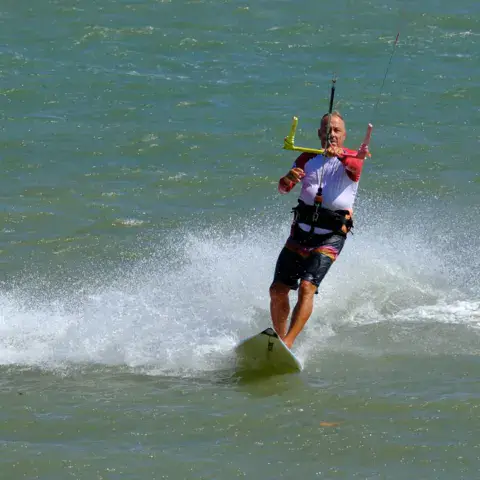 Kitesurfeur filant sur l'eau dans une gerbe d'écume