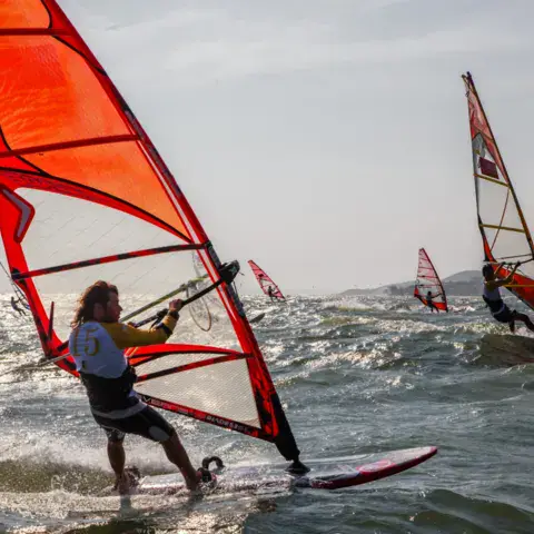 Planchistes sous des voiles rouges sur l'eau