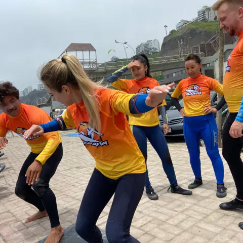 Moniteurs et élèves en lycra orange s'exerçant sur la promenade avant d'entrer dans l'eau