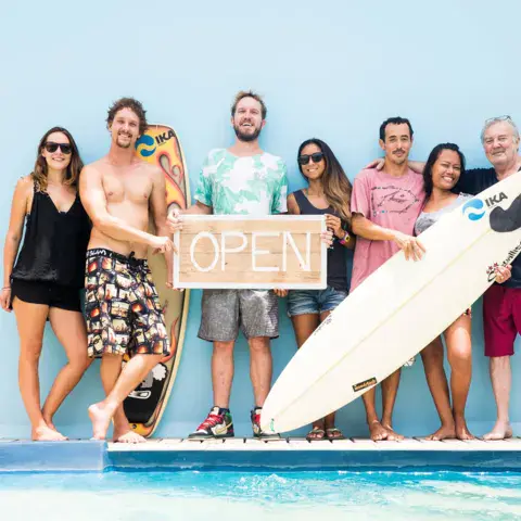 Groupe de clients et d'hôtes au bord de la piscine, avec une planche