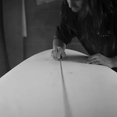 Artisan travaillant sur une planche de surf, photo en noir et blanc