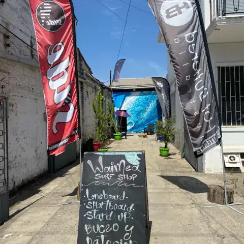 Ruelle d'accès à la boutique avec oriflammes et ardoise