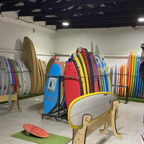 Intérieur de la boutique : planches de surf et combinaisons