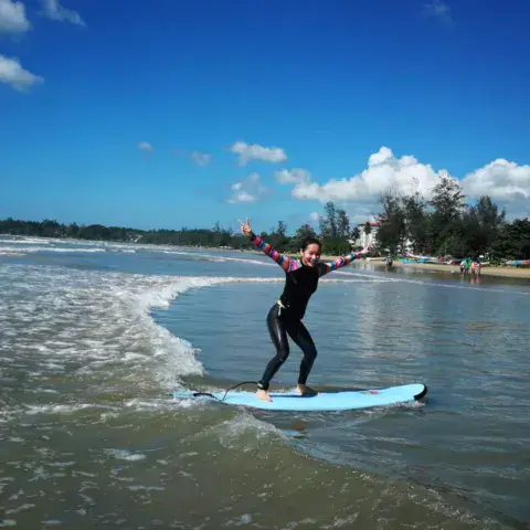Élève debout sur sa planche dans les vagues de la baie