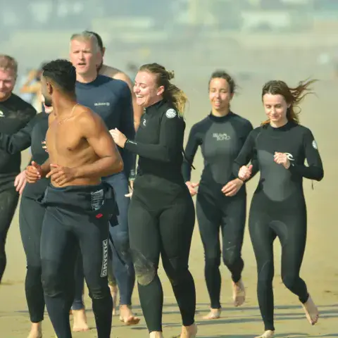 Groupe d'élèves et moniteurs en combinaison sur la plage