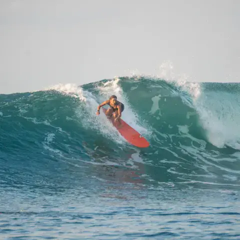 Une surfeuse sur une vague, planche rouge