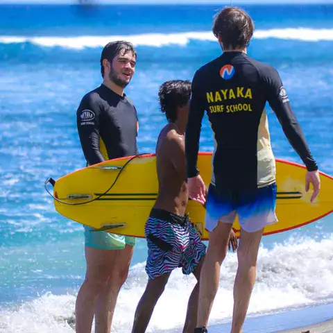 Moniteurs de l'école sur la plage avec une planche jaune