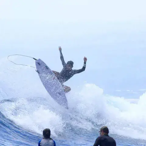 Surfeur en pleine manœuvre sur une vague