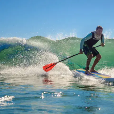 Pratiquant de stand up paddle dans une vague