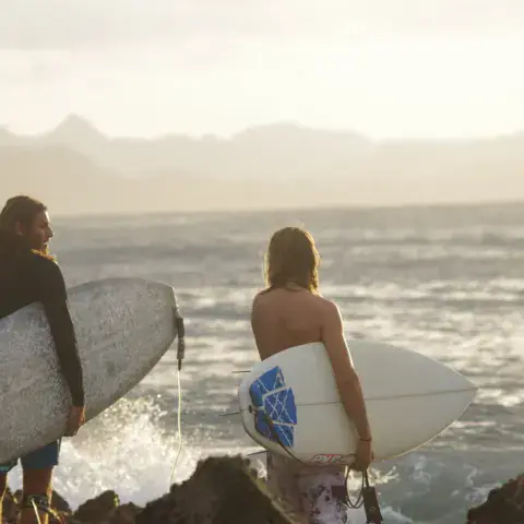 Deux surfeurs face à l'océan avec leurs planches