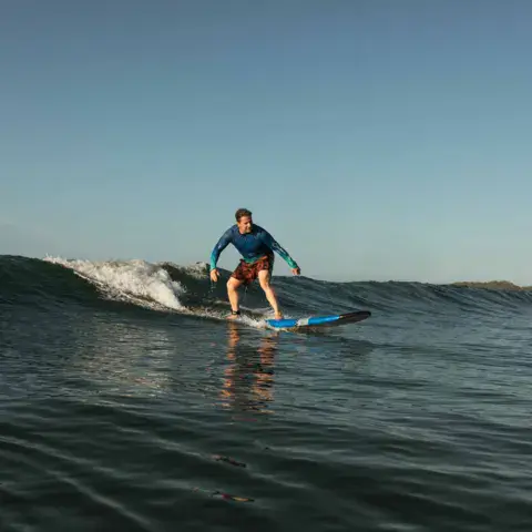 Élève debout sur sa planche sur une vague