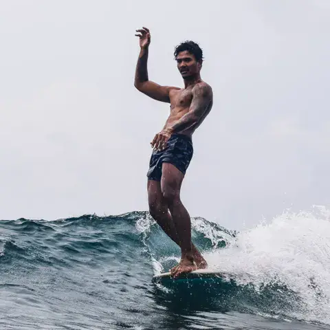 Un surfeur sur sa planche, bras levé