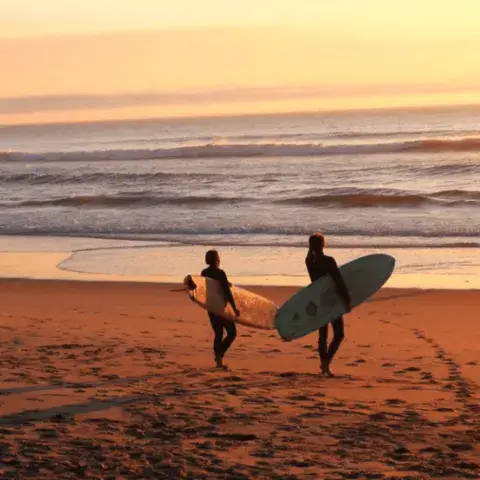 Deux surfeurs avec leurs planches sur la plage au coucher du soleil