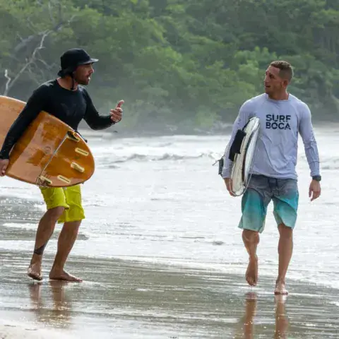 Moniteur et élève avec leurs planches au bord de l'eau