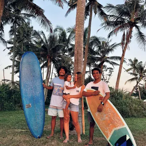 L'équipe de l'école avec des planches, sous les cocotiers
