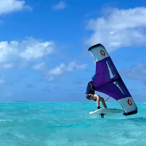 Rider en wing foil sur eau turquoise