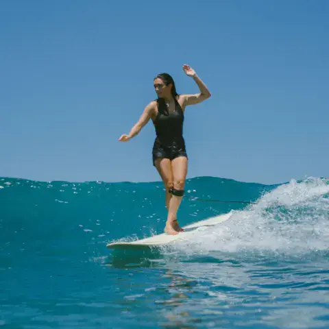 Une surfeuse en longboard sur une vague