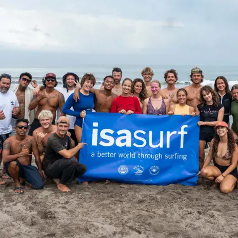 Groupe de stagiaires et d'instructeurs sur la plage avec une bannière ISA
