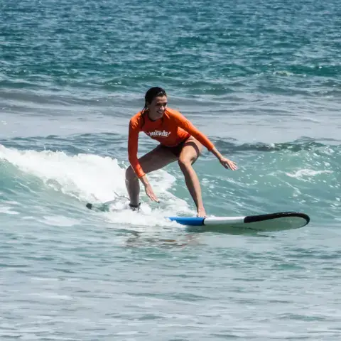 Élève debout sur sa planche dans une petite vague