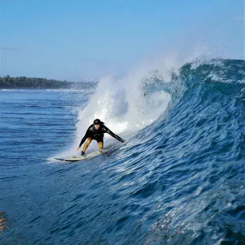 Surfeur au take-off sur une vague bleue