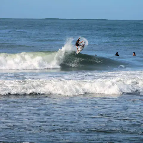 Surfeur sur une vague, d'autres à l'attente derrière