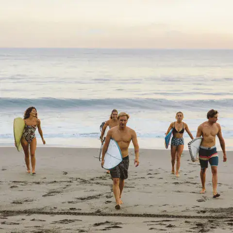 Surfeurs revenant de l'eau avec leurs planches sur la plage