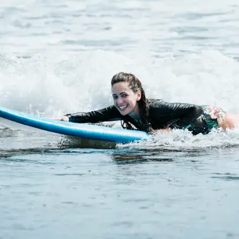 Élève de surf allongée sur sa planche dans l'écume