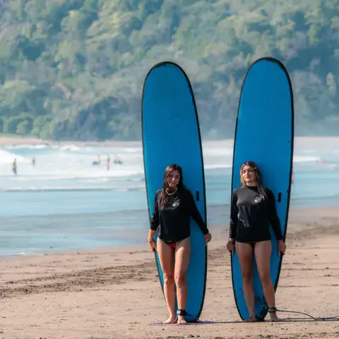 Deux élèves avec leurs planches sur la plage