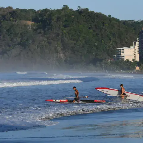Deux surfeurs entrent dans l'eau sur la plage